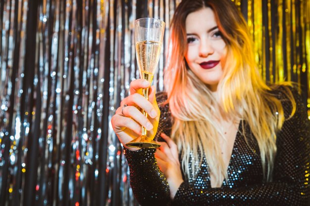 Concetto di celebrazione di nuovo anno con la donna sorridente mostrando vetro di champagne