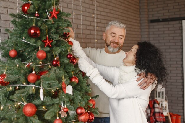 Concetto di età e persone. Coppia senior a casa. Donna in un maglione lavorato a maglia bianco.