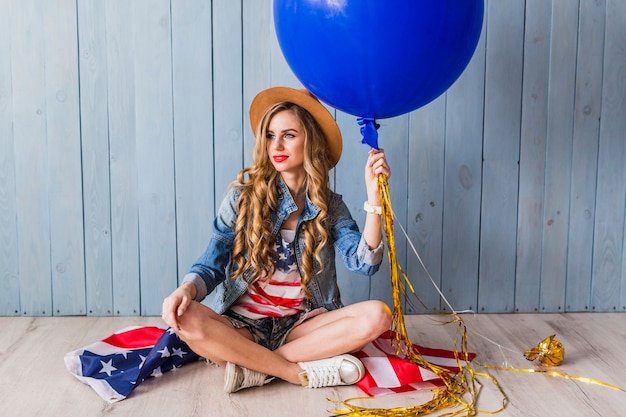 Concetto di festa dell&#39;indipendenza degli Stati Uniti con la donna seduta con palloncino