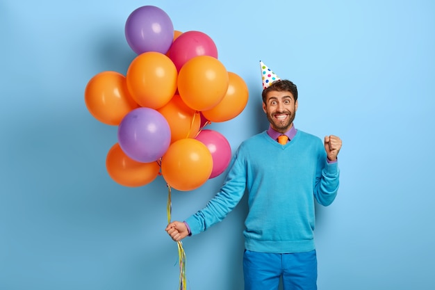 Concetto di festa di compleanno. L'uomo positivo stringe i pugni con felicità