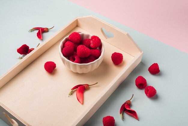 Concetto di fiori adorabili con vassoio in legno e frutti rossi