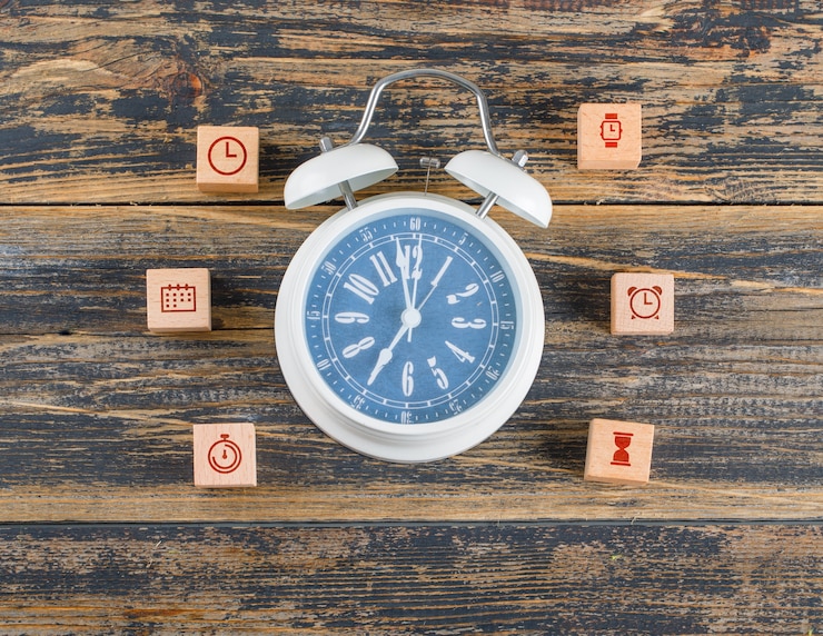 Foto gratuito concetto di gestione del tempo con blocchi di legno con icone, grande orologio sul tavolo di legno piatto laici.