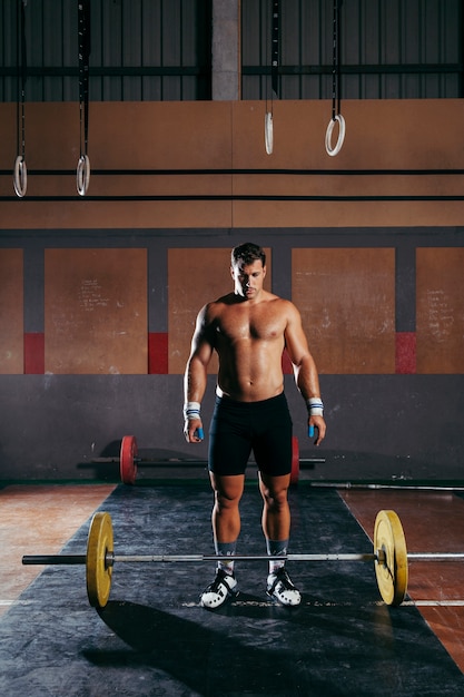 Concetto di ginnastica con un uomo forzato per sollevare il barbell