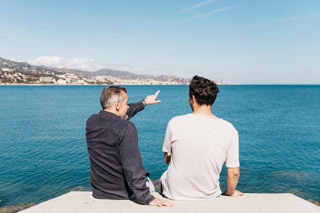 Concetto di giorno di padri con padre e figlio, guardando verso il mare