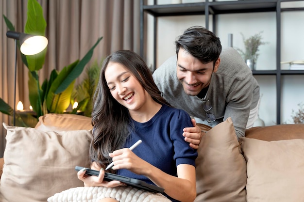 Concetto di isolamento domestico felicità amore asiatico e caucasico coppia famiglia buona conversazione sul divano divano in soggiorno sposare coppia ridere sorridere insieme sul divano