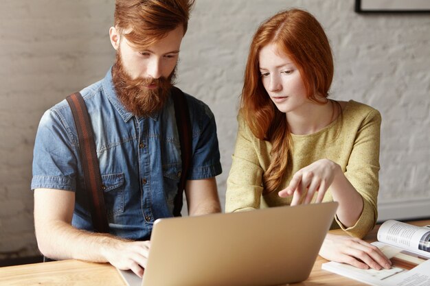 Concetto di lavoro di squadra e cooperazione. Due studenti che lavorano insieme su un progetto comune utilizzando il computer portatile.