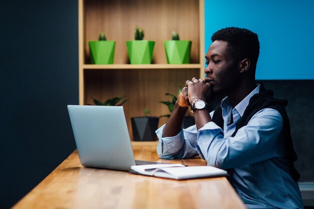 concetto di libero professionista. L'uomo in abiti casual sta esaminando i documenti mentre lavora con un laptop in cucina. Lavorare a casa.