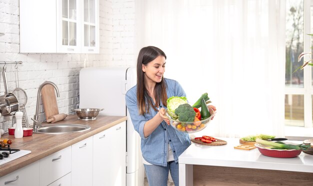 Concetto di mangiare sano. Giovane bella donna in cucina con frutta e verdura. Cibo vegano