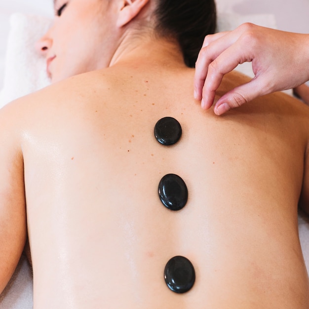 Concetto di massaggio con pietre sulla schiena della donna