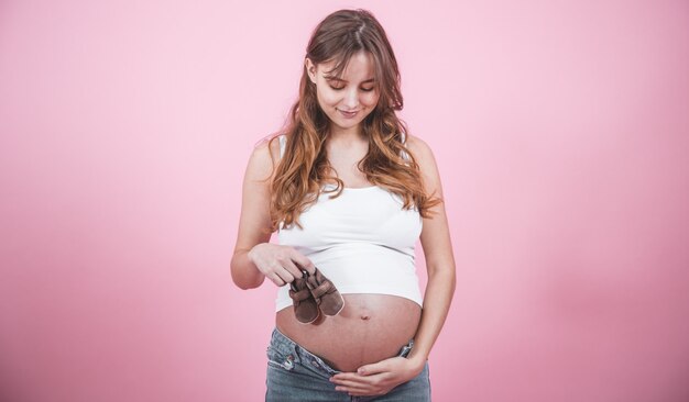 Concetto di maternità, donna incinta con pantofole in mano