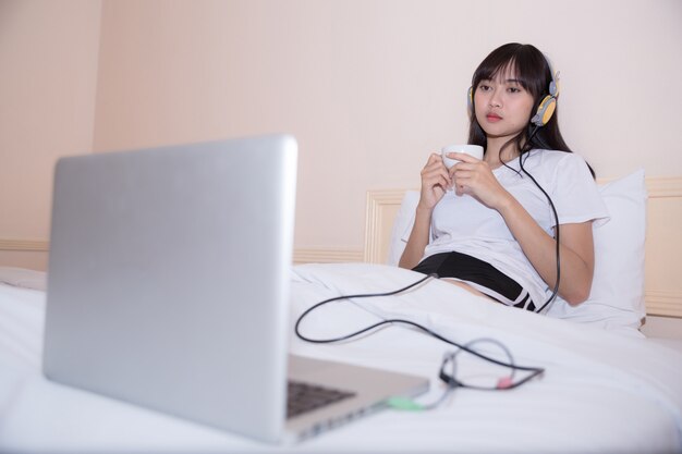 concetto di mattina, di svago, di natale e della gente - giovane donna felice con la camera da letto della camera da letto o della tazza di caffè o del tè a casa