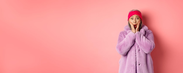 Concetto di moda vecchia donna asiatica alla moda che guarda sorpresa alla macchina fotografica femmina matura in cappotto viola e