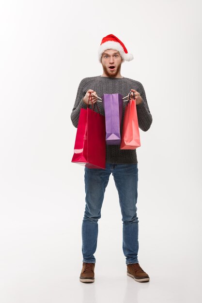 Concetto di Natale attraente giovane uomo caucasico sorprendente regalo scioccante nella borsa della spesa