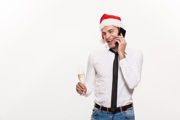 Concetto di Natale Bell'uomo d'affari che parla al telefono e tiene un bicchiere di champagne per celebrare il Natale e il nuovo anno