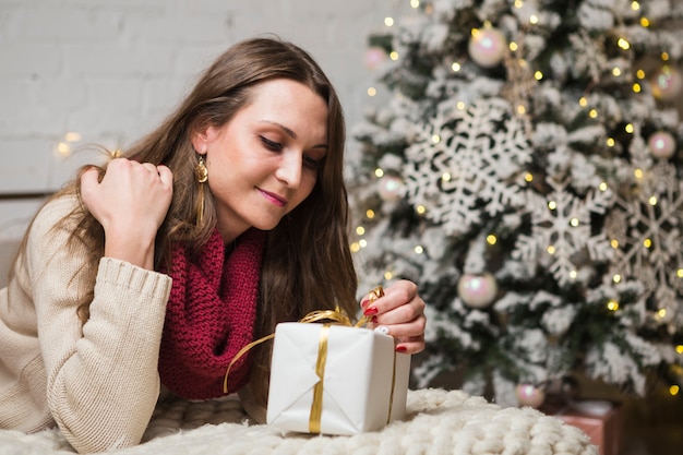 Concetto di Natale con donna che apre piccolo regalo