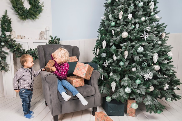 Concetto di Natale con i bambini sul divano accanto all&#39;albero di Natale