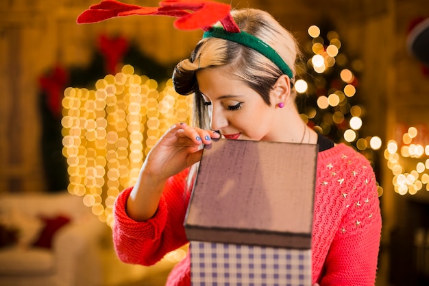 Concetto di Natale con il contenitore di regalo biondo della tenuta della donna