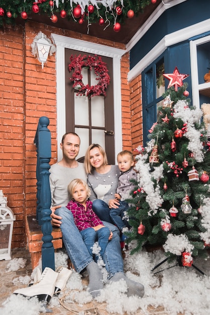 Concetto di Natale con la famiglia seduto di fronte a casa