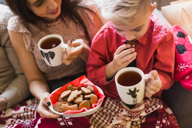 Concetto di Natale con la madre e il ragazzo con tè e biscotti