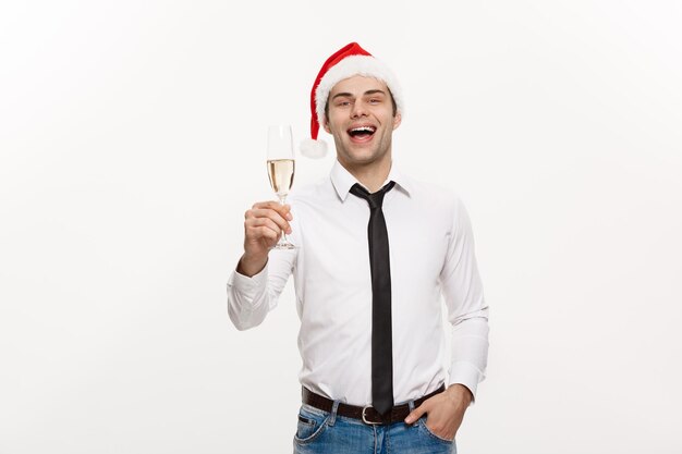 Concetto di Natale L'uomo d'affari bello festeggia il buon Natale e il felice anno nuovo indossa un cappello da Babbo Natale con un bicchiere di champagne