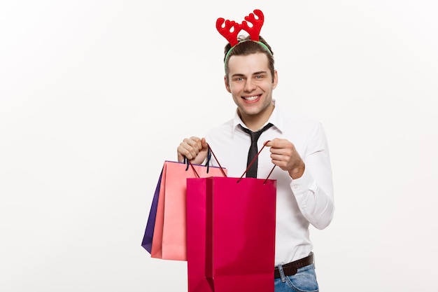 Concetto di Natale L'uomo d'affari bello festeggia il buon Natale e il felice anno nuovo, indossa una fascia per capelli con renne e tiene in mano la borsa grande rossa di Babbo Natale