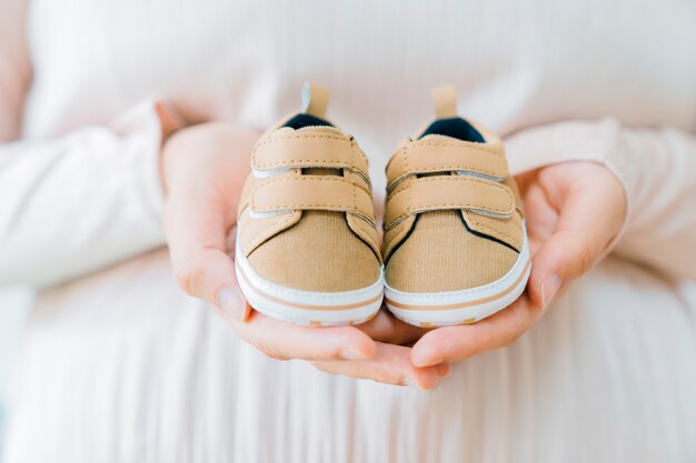 Concetto di neonato con le mani che tengono le scarpe