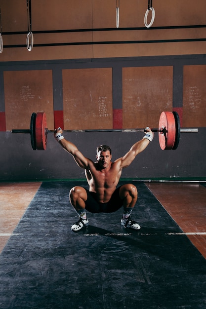 Concetto di palestra con bilanciere di sollevamento forte dell&#39;uomo