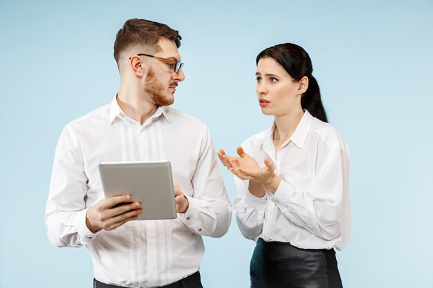 Concetto di partnership nel mondo degli affari. Giovane uomo emotivo e donna su sfondo blu in studio. Le emozioni umane e il concetto di partnership