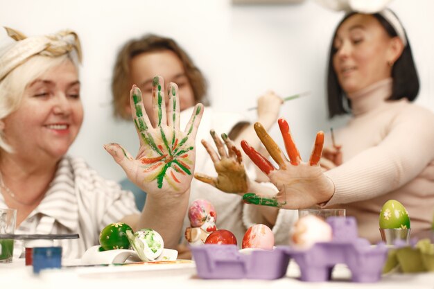 Concetto di Pasqua. Bambina e sua nonna colorare le uova per Pasqua. Grande famiglia a casa.