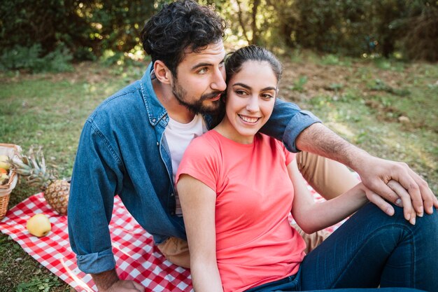 Concetto di pic-nic con le coppie che si siedono in natura