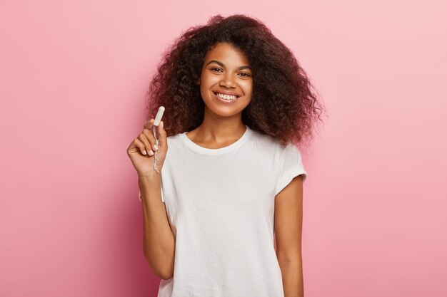 Concetto di protezione dell'igiene delle donne. La femmina dalla pelle scura allegra tiene il tampone di cotone