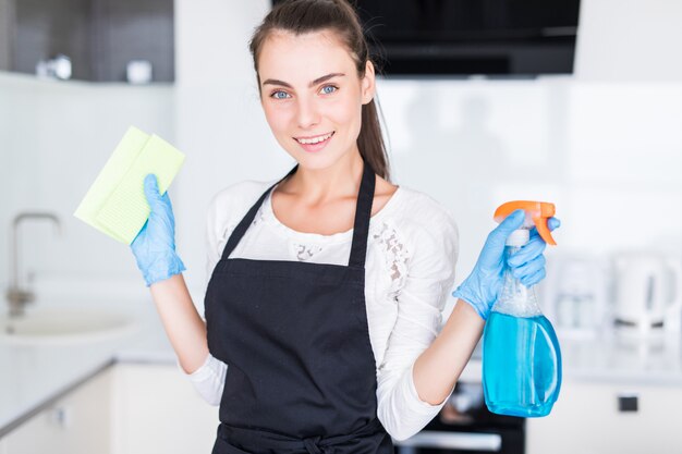 Concetto di pulizia. Strumenti di pulizia della tenuta della giovane donna nella cucina