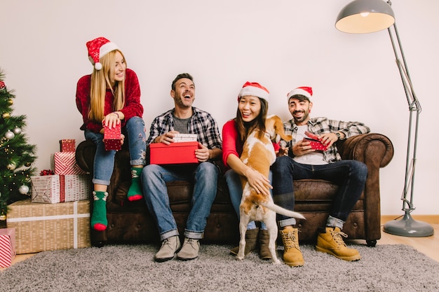 Concetto di regalo di Natale con quattro amici sul divano e cane