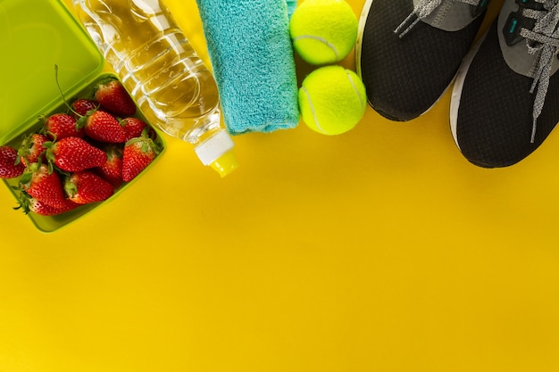 Concetto di salute sano della vita. Sneakers con frutta, asciugamano e bottiglia di acqua su sfondo in legno. Spazio di copia.