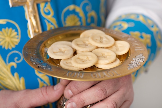 Concetto di santa comunione con il sacerdote che tiene il cibo