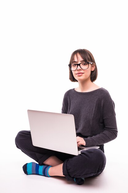 Concetto di scuola, istruzione, internet e tecnologia - giovane ragazza adolescente seduta sul pavimento con il computer portatile