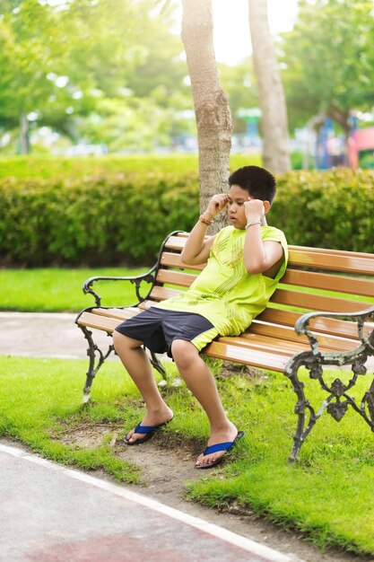 Concetto di sport Il piccolo corridore sportivo si siede sulla pista e fa un respiro profondo sentirsi stanco e annoiato