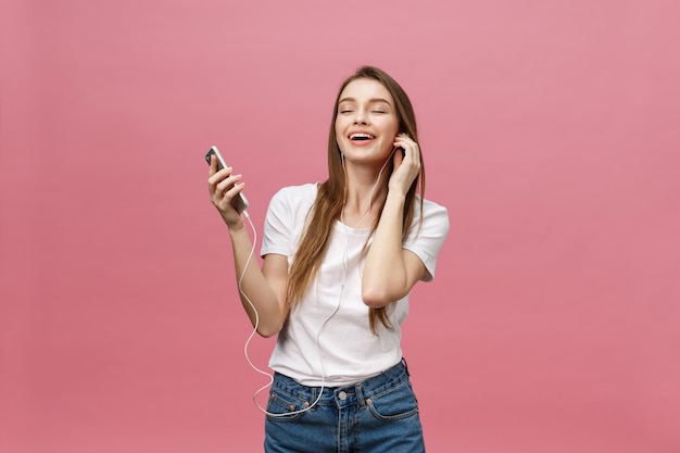 Concetto di stile di vita Giovane donna che usa il telefono per ascoltare musica su sfondo rosa