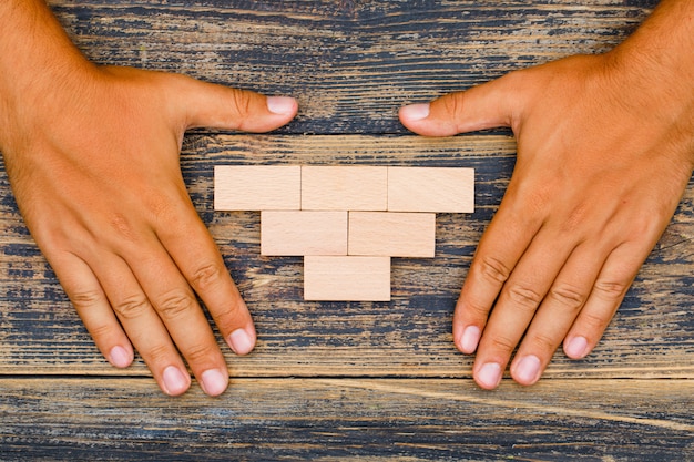 Concetto di strategia aziendale sulla disposizione di legno del piano del fondo. mani che proteggono i blocchi di legno.