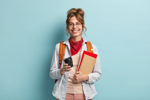 Concetto di studio, tempo libero e stile di vita. La ragazza europea ha un sorriso sincero, torna dall'università di buon umore, beve caffè