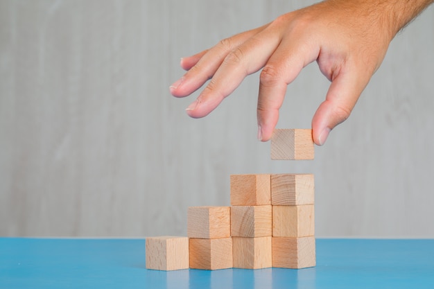 Concetto di successo di affari sulla vista laterale della tavola blu e grigia. raccolta a mano cubo di legno.