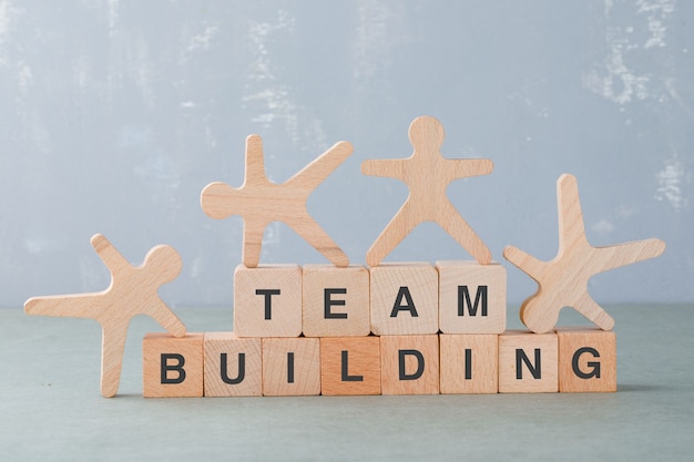 Concetto di team building con blocchi di legno, figure umane in legno su di esso vista laterale.