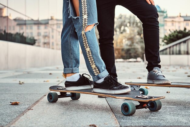 Concetto di tempo libero e sport - foto ravvicinata di una coppia adolescente vestita alla moda con skateboard per strada.