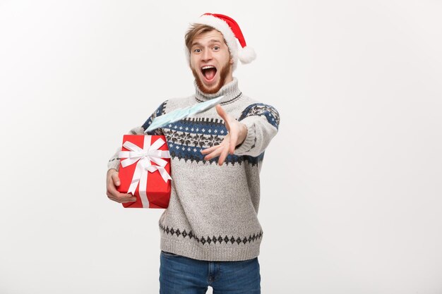 Concetto di vacanza Giovane uomo con la barba che tiene un regalo di natale e lancia soldi alla fotocamera