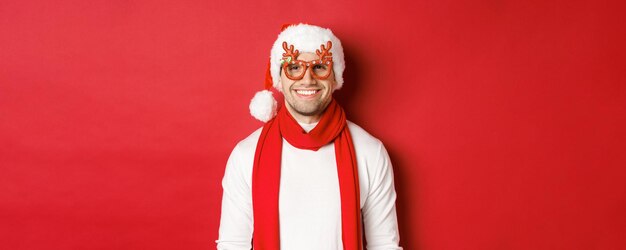 Concetto di vacanze invernali di natale e celebrazione allegro bel ragazzo con gli occhiali da festa di capodanno...