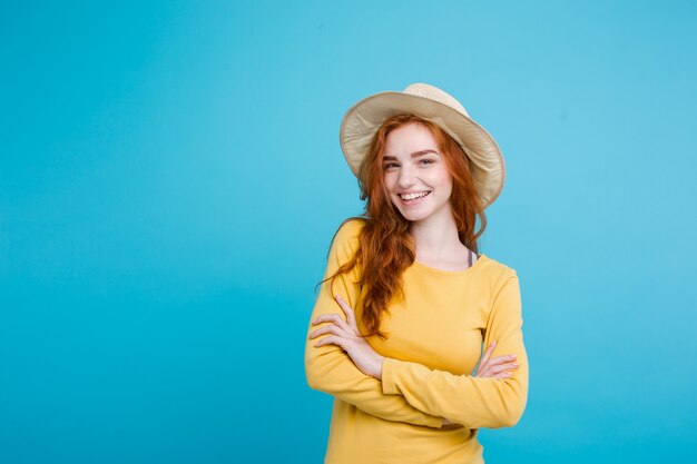 Concetto di viaggio - Close up Ritratto di giovane bella ragazza attraente redhair con cappello alla moda e sorridente sunglass. Sfondo blu pastello. Copia spazio.