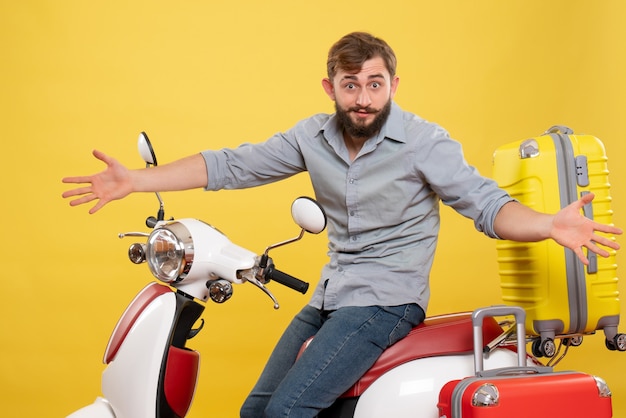 Concetto di viaggio con giovane barbuto curioso emotivo che si siede sulla moto su di esso su colore giallo