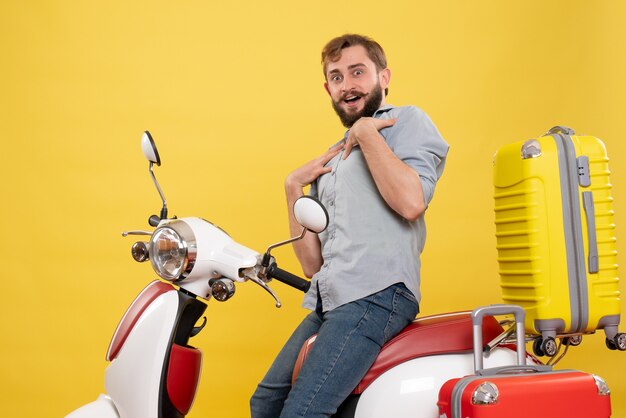 Concetto di viaggio con il giovane uomo barbuto chiedendo che si siede sulla moto e che punta su di esso su giallo