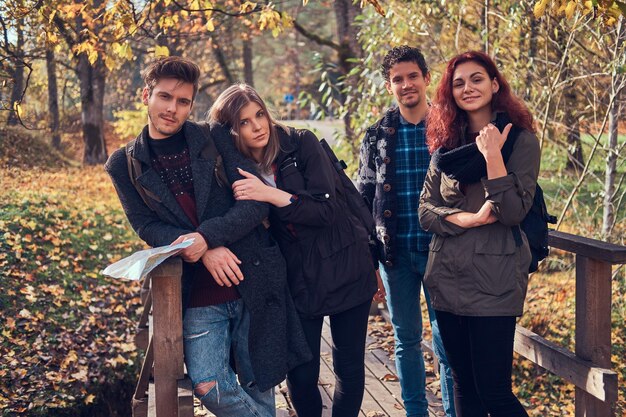 Concetto di viaggio, escursionismo, avventura. Gruppo di giovani amici che fanno un'escursione nella foresta variopinta di autunno.