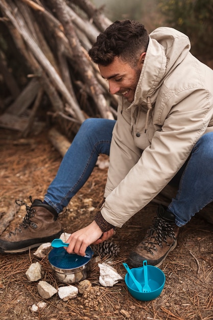 Concetto di vita del campeggiatore con l'uomo che cucina in natura